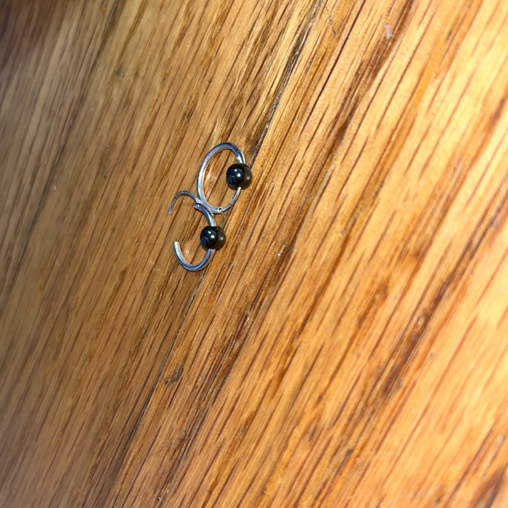 Small round earring has a black ball on it.